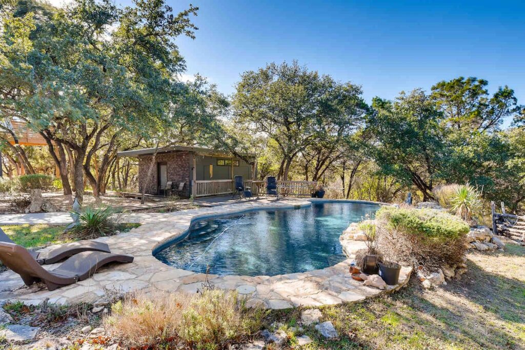 Natural stone swimming pool beside The Cabin at Eco Valley with lounge chairs, shaded deck, and mature trees creating a serene forest retreat atmosphere