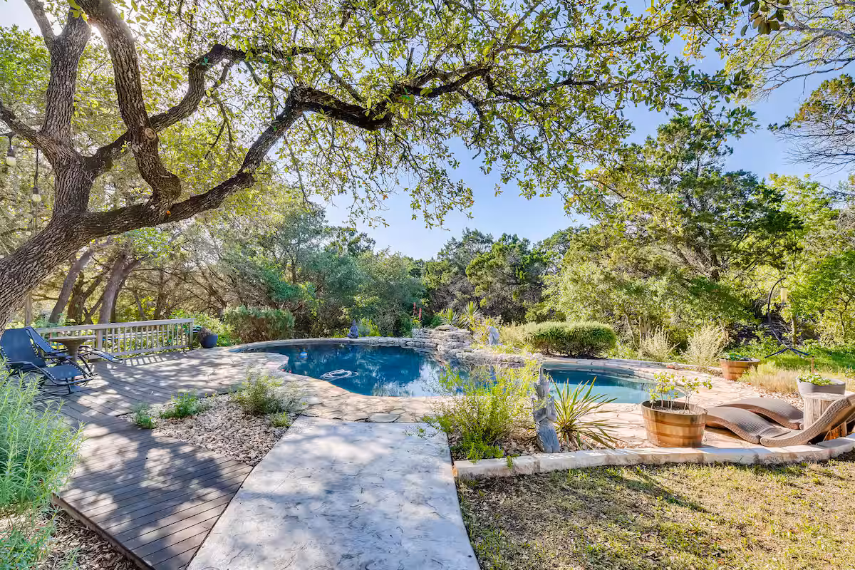 Natural pool area near The Cabin with stone decking, shaded lounge seating, and mature trees