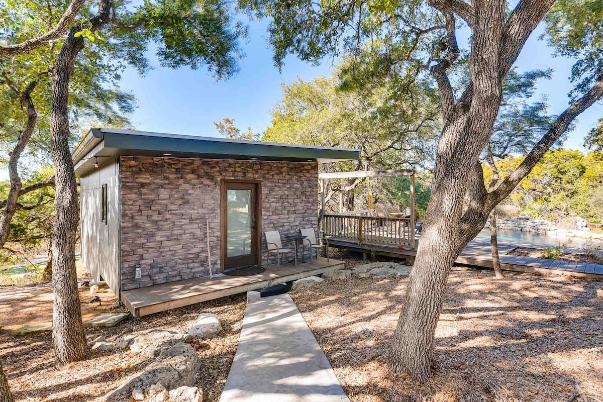 Exterior of The Cabin featuring a private deck, shaded seating, and surrounding mature trees