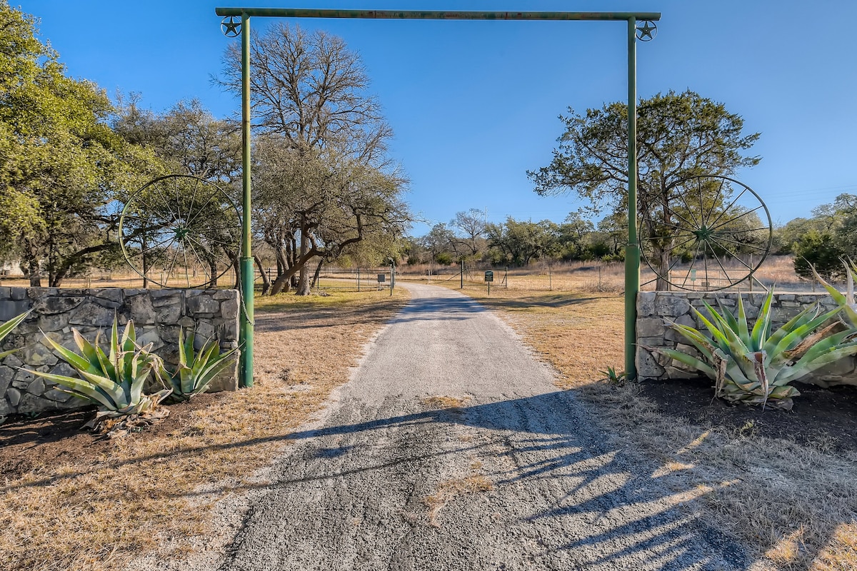 Rustic ranch entrance with a gravel drive and metal gate.