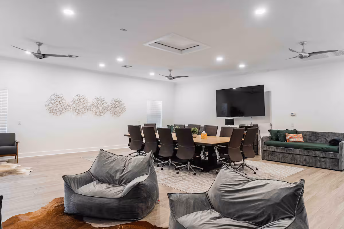 Casa Blanco meeting space with conference table, bean bag seating, and wall-mounted TV.