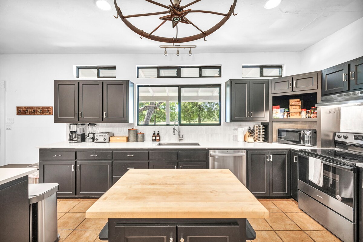 Casa Blanco kitchen with black cabinets, butcher-block island, and modern appliances.