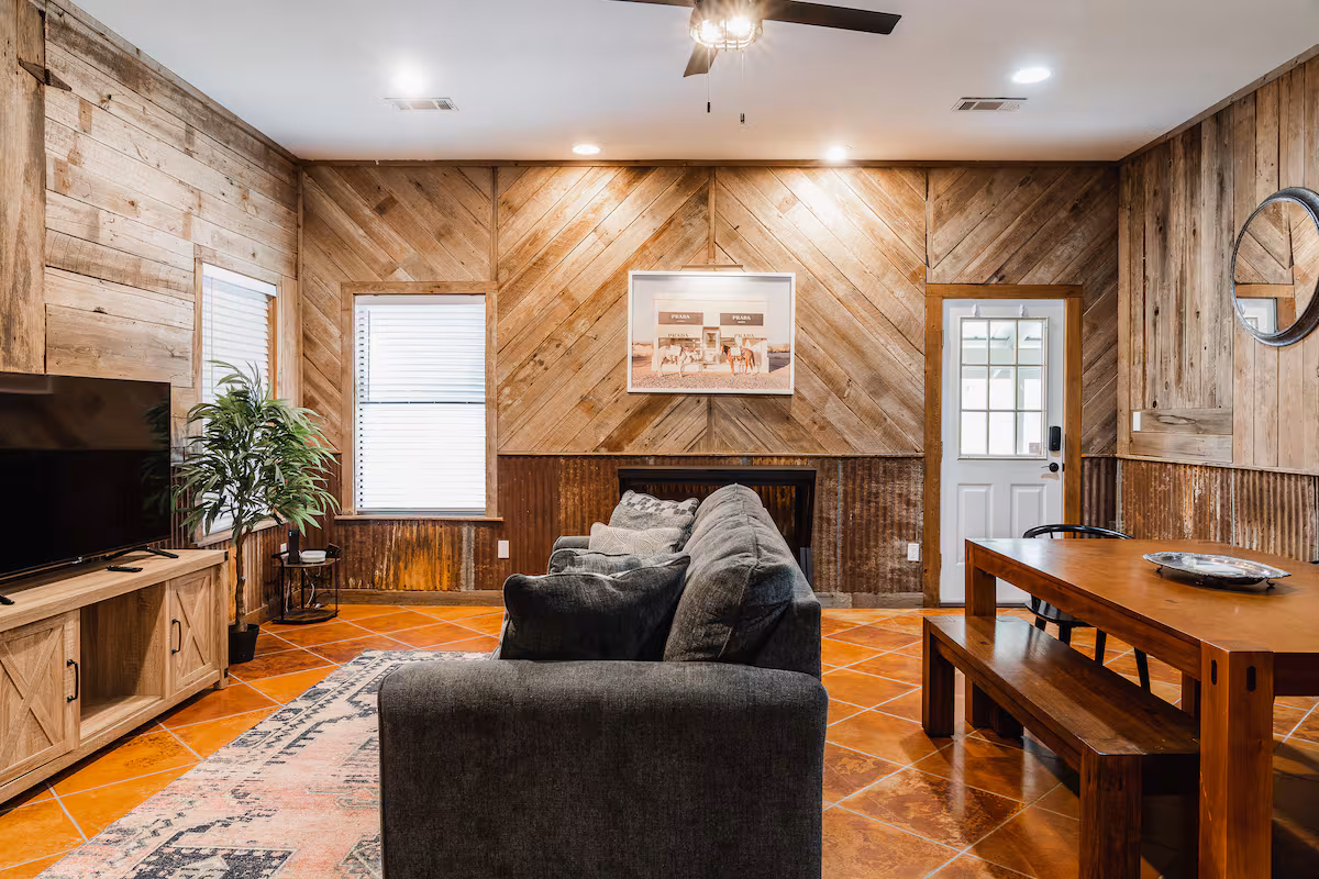 Cowboy Apartment living and dining area with rustic wood walls and cozy seating.