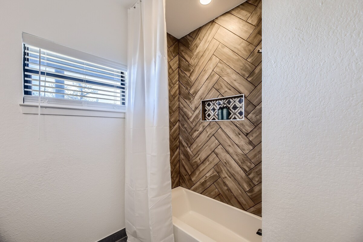 Bathroom tub and shower at The Villa with herringbone tile accent and natural light.