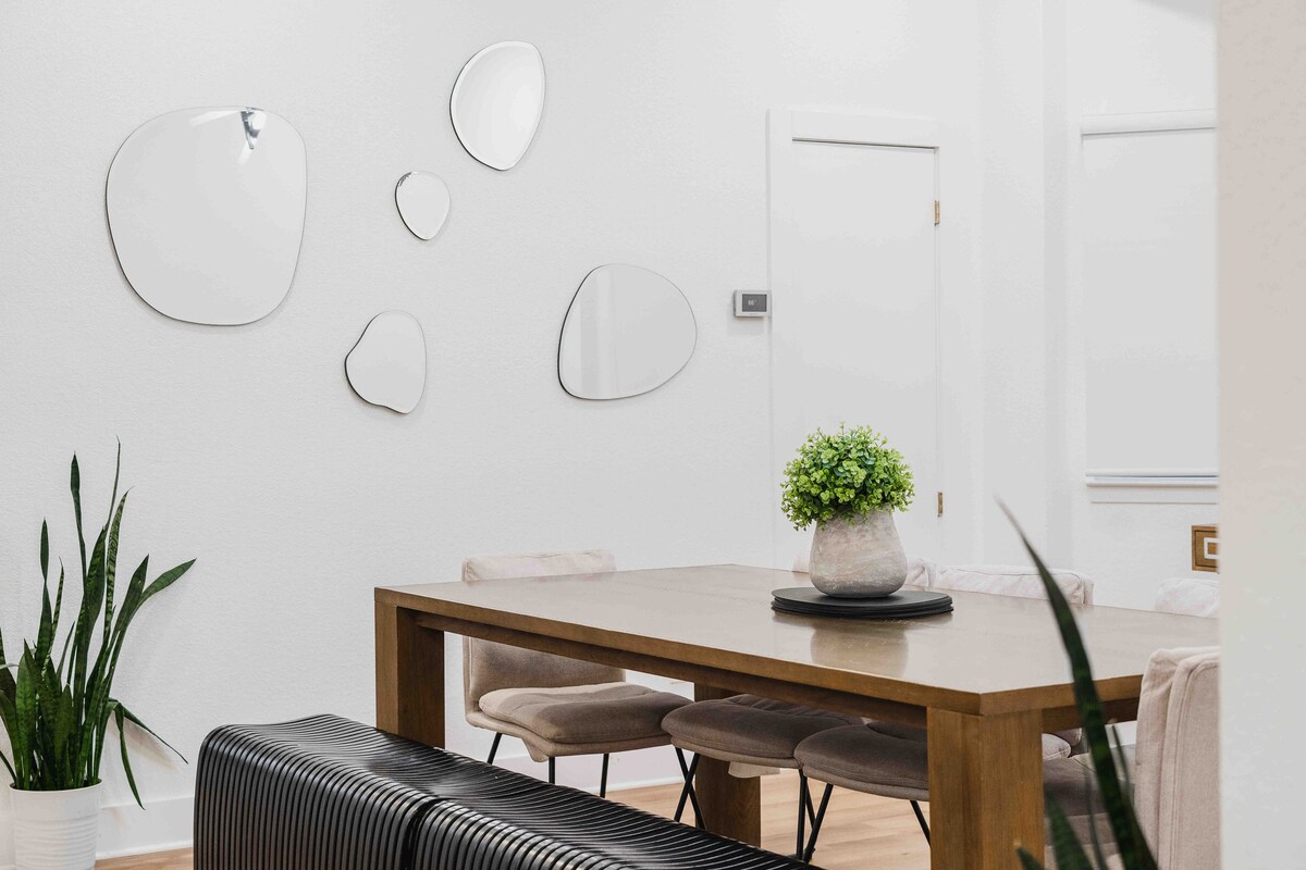 Dining area in The Villa with wood table, upholstered seating, modern wall mirrors, and minimalist decor
