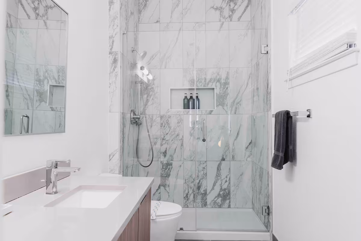 Modern bathroom in The Villa with glass-enclosed shower, marble tile walls, and sleek vanity
