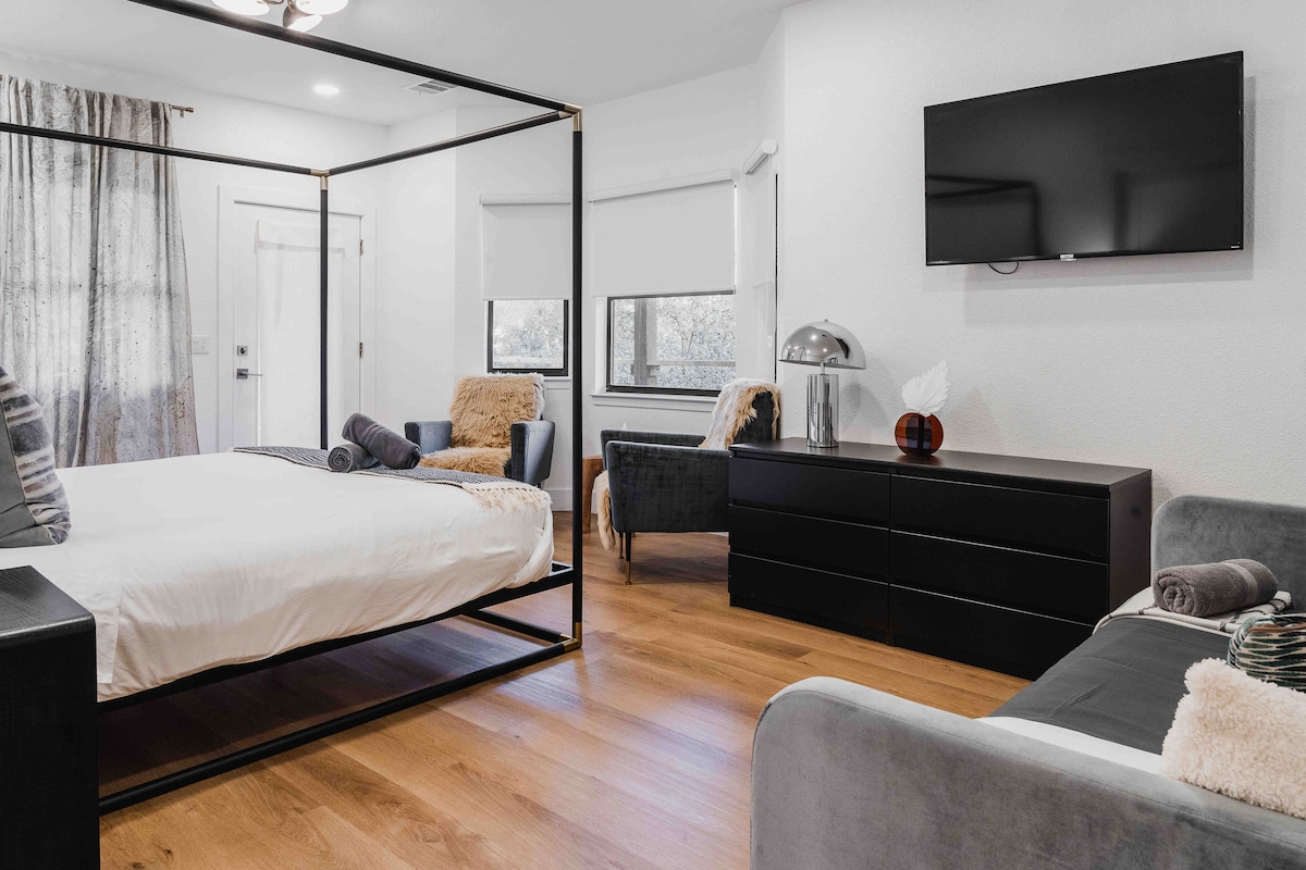 Bedroom in the villa with a modern four-poster bed, seating area, and wall-mounted TV.