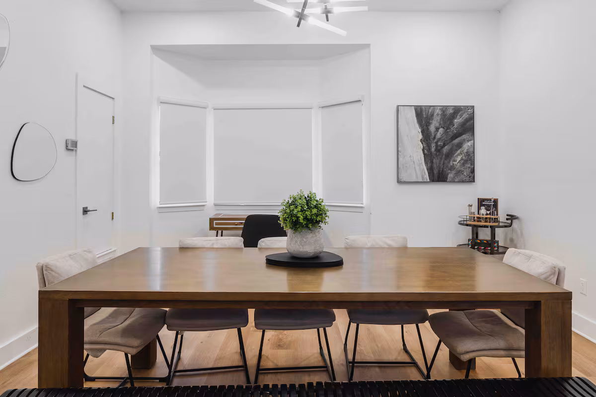 Dining room in the villa with a large wooden table, upholstered chairs, and bright bay window.