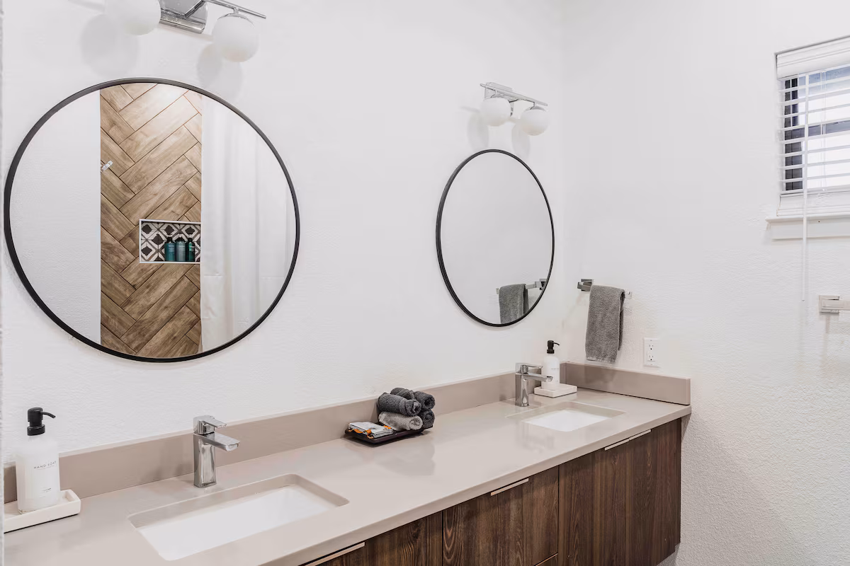 Modern bathroom in the villa with double vanity, round mirrors, and clean minimalist finishes.