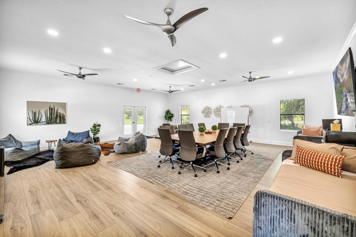 Open lounge and meeting space at High Tech Hacienda with large table, modern seating, and ceiling fans.