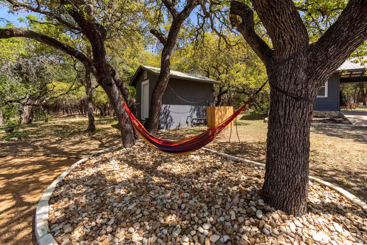Hammock area at The Nook at Eco Valley with a colorful hammock strung between oak trees, gravel ground cover, and a quiet woodland setting