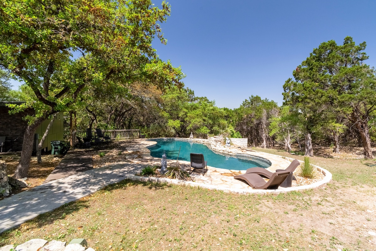 The Nook at Eco Valley featuring a natural stone swimming pool nestled among trees with lounge chairs and a peaceful wooded setting