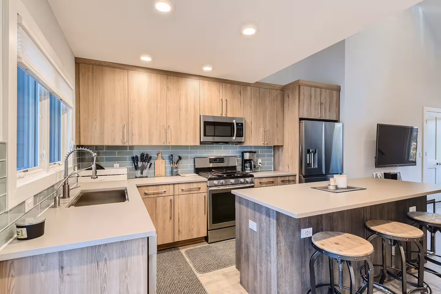 The Loft kitchen with wood cabinets, a large island, bar stools, and stainless steel appliances.