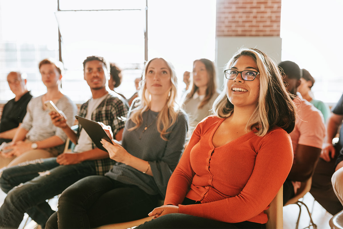 Group of attendees seated indoors, listening attentively during a group presentation or workshop.
