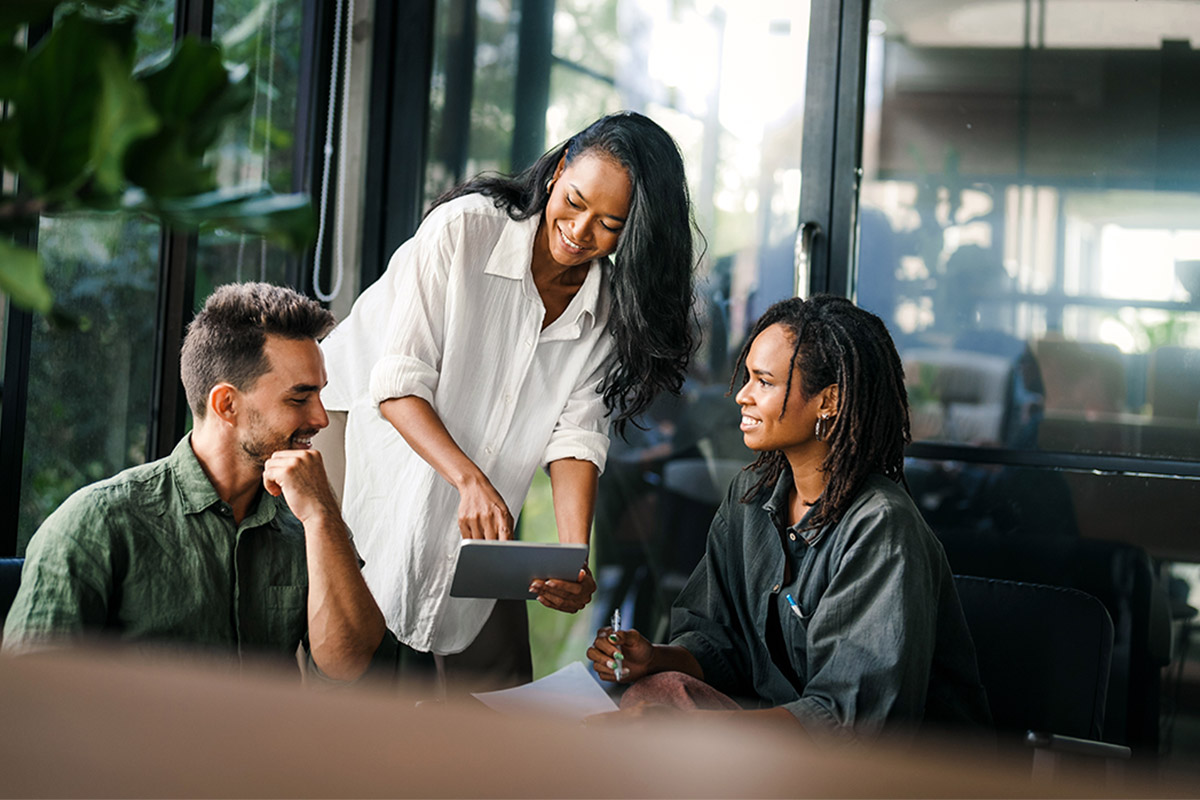 Team retreat participants collaborating around a tablet during a group work session.