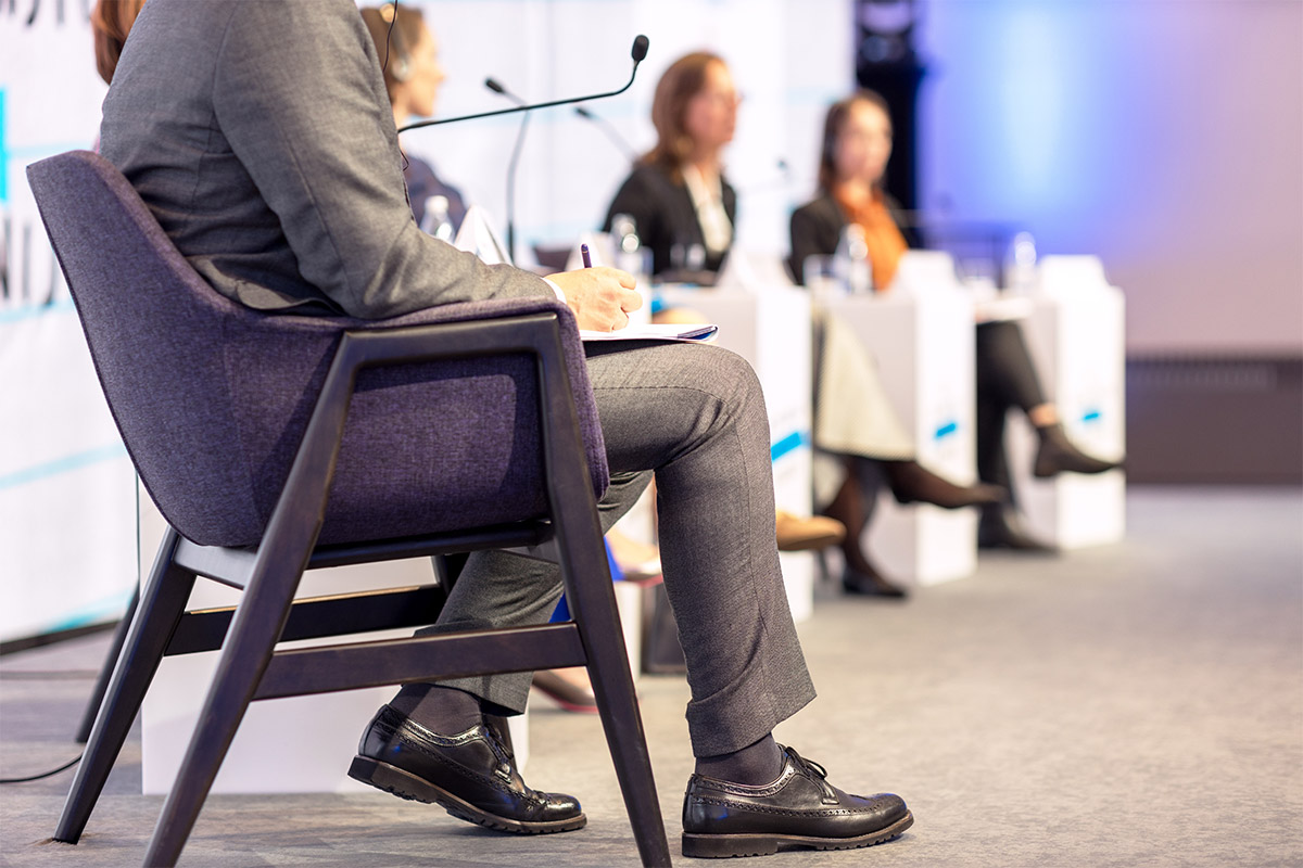 Speakers participating in a panel talk on stage during a professional event.