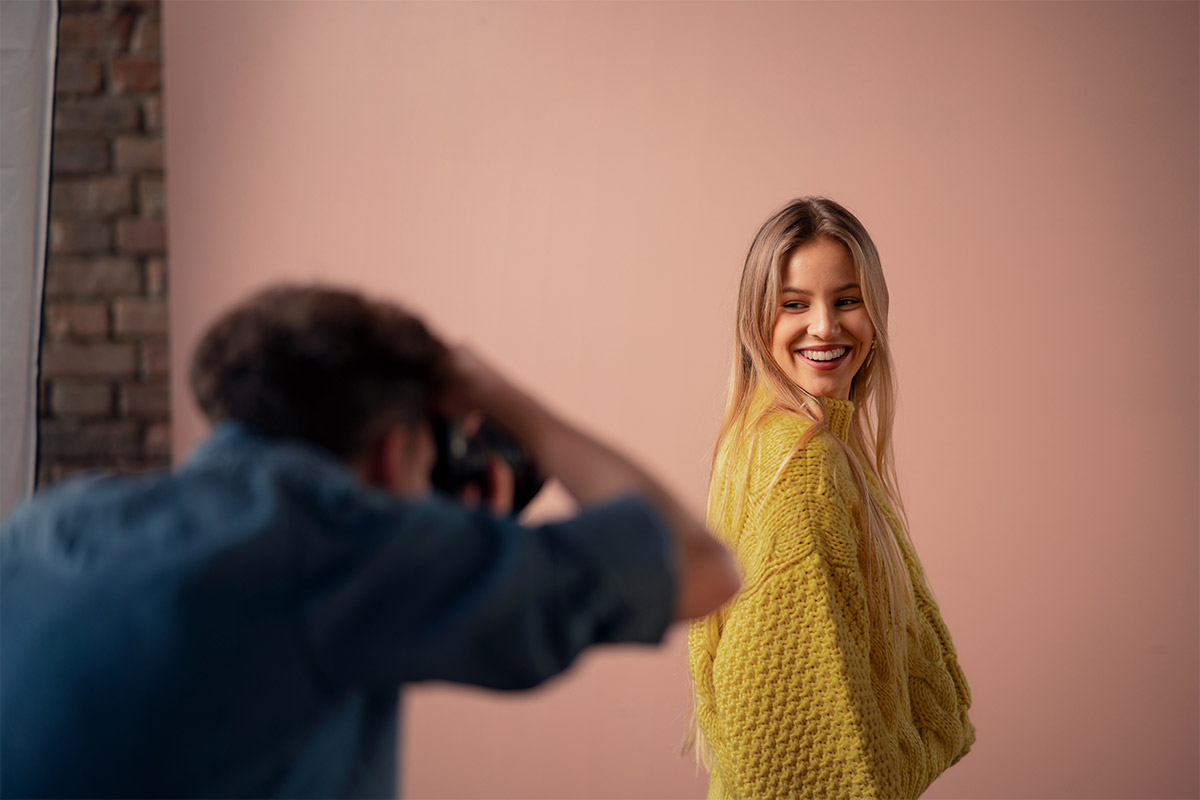 Person smiling while being photographed during an indoor photoshoot.