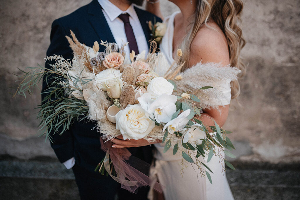 Bride and partner holding a bouquet at a small micro wedding celebration.